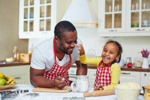 Joyful girl having fun with her father while cooking pastry